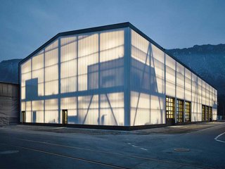 Die Fassade aus transluzenten Polycarbonplatten gibt des Nachts die Silhouette des Holztragwerks frei.
