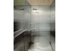 Ungewöhnliche Badgestaltung: Wände und Boden aus Chromstahlplatten setzen einen kühlen Kontrast zur unbehandelten Brettstapeldecke aus Holz.