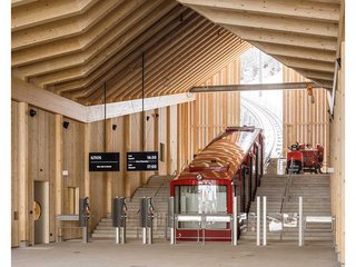 Die Standseilbahn, deren Waggons neu gestaltet und gebaut wurden, steht schräg im Bahnhofsbau. Die Neigung nimmt der Holzbau in Form eines Dachknicks auf und macht diese so auch nach aussen sichtbar.
